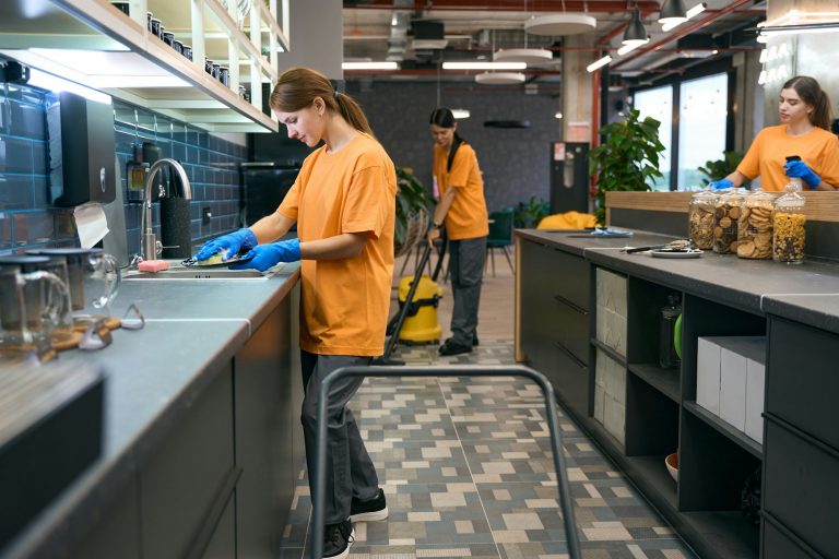 Team cleaners do general cleaning in kitchen area coworking space