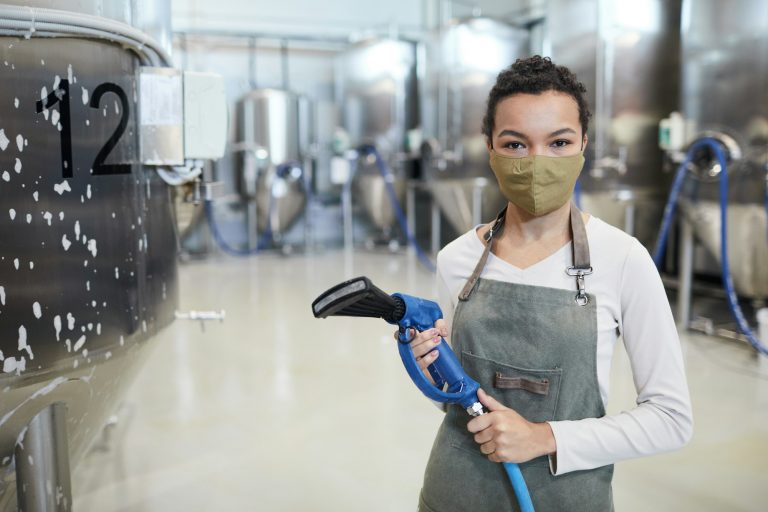 Young Woman Cleaning Workshop at Factory