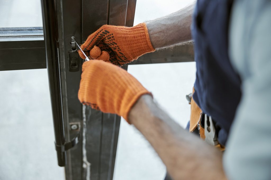 Male worker hands repairing door lock in house